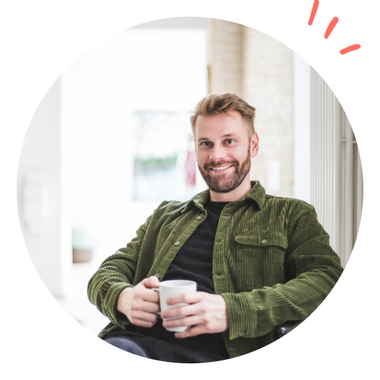 En glad leder smiler med en kaffekopp i hånden