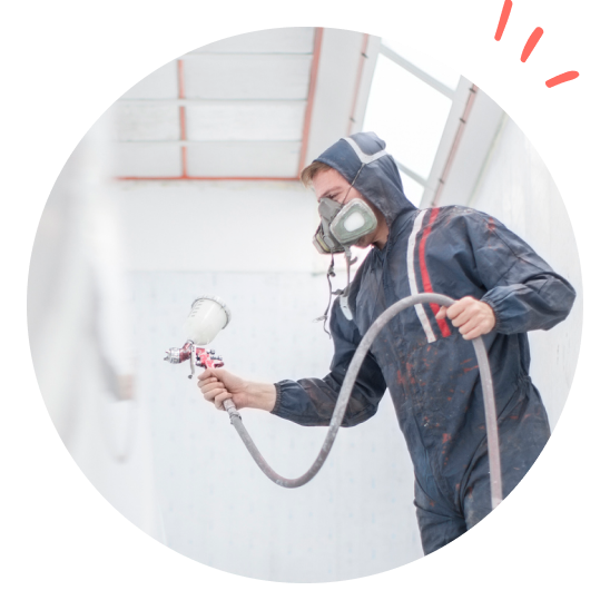 Man with mask and safety suit spray-painting indoors.